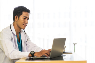 Asian man doctor wearing uniform with stethoscope working with laptop computer with virtual screen...