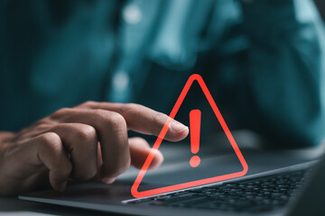 Businessman use laptop with virtual warning sign for caution in investing economic situation...