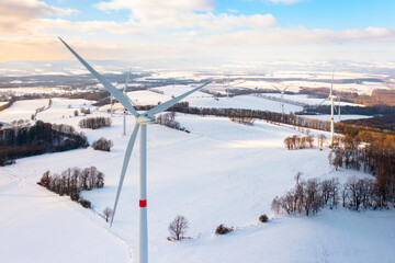 Winter meadow with wind turbines generating electricity. Green energy concept. 
