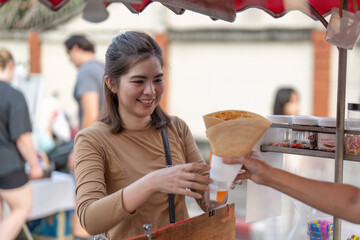 Happy young Asian Traveler foodie woman order Crepes at outdoor night market street food vendor