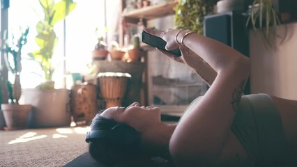 Woman, smartphone and social media, headphones and relax on living room floor with communication and music. Typing, scroll and chat with mobile app, listening to podcast or radio playlist at home