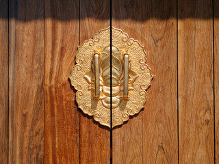 Brass carved door handle on the wooden door of Chinese temple, beautiful lotus or clouds style door handle.