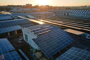 Aerial view of blue photovoltaic solar panels mounted on industrial building roof for producing...