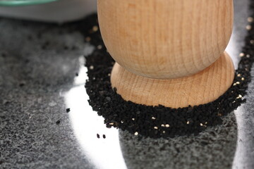 Black cumin seeds and mortar on granite slab