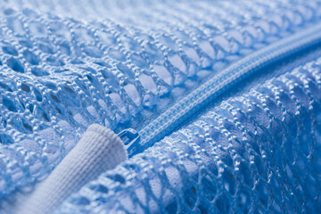 Close up shot of plastic zipper attached to blue nylon mesh bag.