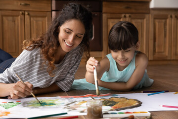 Funny artists. Smiling latina family young foster mother and small daughter adopted child paint big...