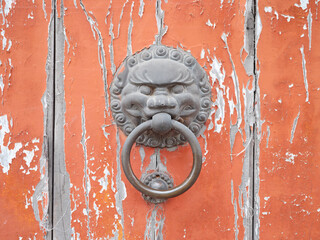 Old Chinese style door handle on wooden door, antique oriental door knocker. Traditional Chinese doors with brass lion head door knockers