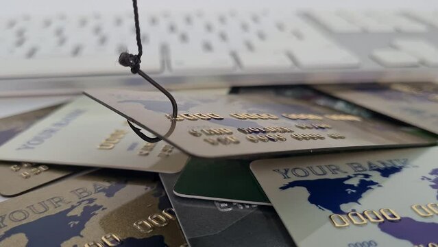 Phishing fishhook with credit card on white computer keyboard. Credit card fraud