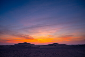 Fototapeta na wymiar desert sand dune with beautiful clouds after sunset.