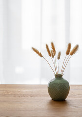 Wooden oak table top with a green vase with dry flowers