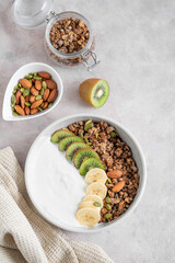 Granola with banana and kiwi on a light background with a napkin.