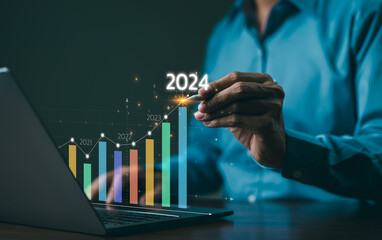 The 2024 New Year business goals concept. Businessman analyzes graph of trend market growth in 2024 and plans business growth and profit increases. calculates financial data for long-term investments. - obrazy, fototapety, plakaty