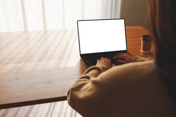 Mockup image of a woman working and typing on laptop computer with blank white desktop screen at home