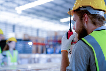 The manager uses a walkie-talkie to communicate safety and quality control policy with workers on...
