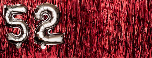 Silver foil balloon number fifty-two. Birthday or anniversary card with the inscription 52. Red...