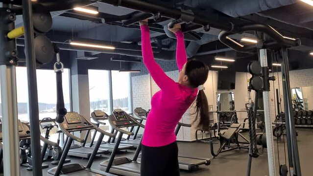 Woman is training in gym and doing pull-ups on bars. Healthy lifestyle sport and strength