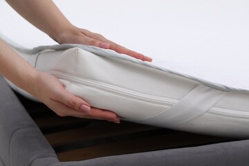 Woman putting new soft mattress on bed, closeup