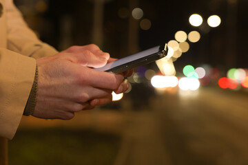 Man using smartphone on night city street, closeup. Space for text
