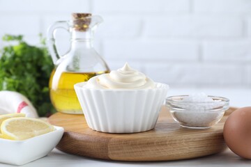 Fresh mayonnaise sauce in bowl and ingredients on table