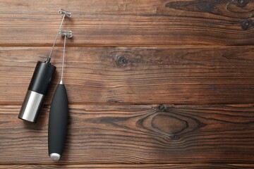 Black milk frother wands on wooden table, top view. Space for text