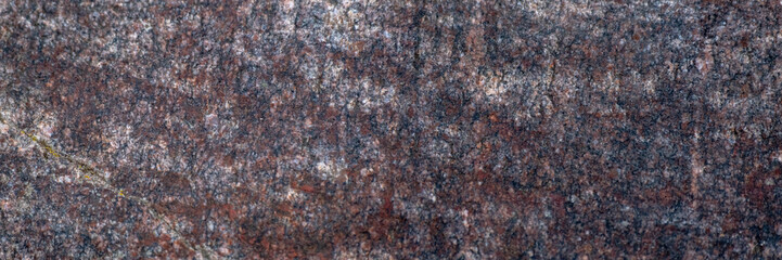 Red granite texture. A variegated, spotted background of red with dark gray rough granite. The stone granite surface of brown-gray color. Surface view of granular igneous rock