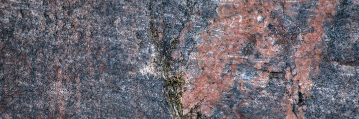 Red granite texture. A variegated, spotted background of red with dark gray rough granite. The stone granite surface of brown-gray color. Surface view of granular igneous rock