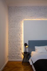 Interior of a modern bedroom with a white brick wall and a bed