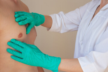 a doctor in green gloves examines a man's chest. Prevention of breast diseases in men. Men's health