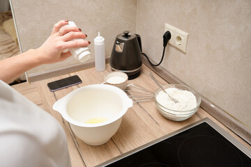 Woman preparing dough in the kitchen, close-up of hands.