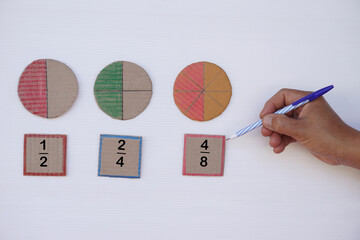 Math teaching materials about fraction. Hand hold pen. Circle paper  show parts of color separation. Concept, education. DIY craft as teaching aid in Math subject.                