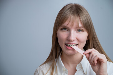 Young woman with metal braces on her teeth is chewing gum. Copy space. 