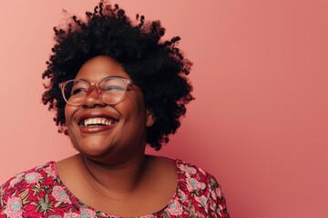 Smiling plussize black woman in eyeglasses poses happily.