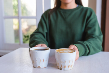 Closeup image of a woman holding and serving two cups of hot coffee