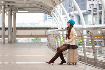 Young female traveler with a suitcase at the modern transport stop outdoors