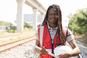 African American female engineer working and performing railway maintenance, wearing safety uniform and helmet