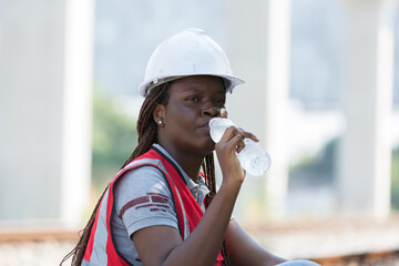 African American female engineer drinking water at construction site railway maintenance