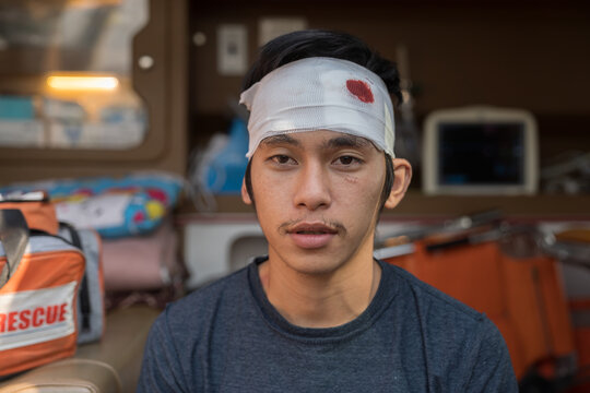 Paramedics help asian male injured had a broken head and bandage during sitting in ambulance car