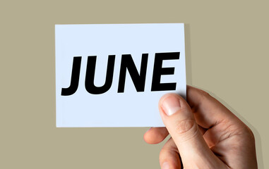 June month displayed on hand holding paper isolated on color background.