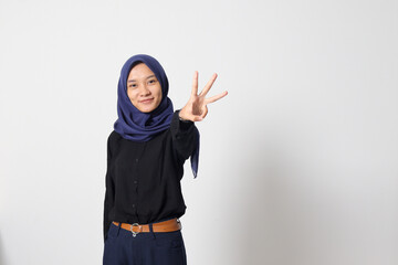 Portrait of excited Asian hijab woman in casual suit showing and pointing up with fingers number three while smiling confident and happy. Businesswoman concept. Isolated image on white background