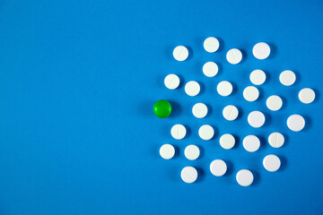 White and green pills lie on a blue monophonic background