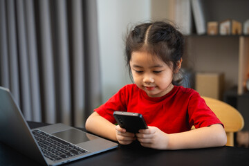 Asian child girl looking using and touch mobile phone screen. Baby smiling funny time to use mobile...