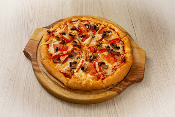 Chicken pizza with mushrooms. On a light wooden background.