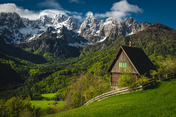 Fototapeta na wymiar Cozy small hut on the slope and snowy mountains, Slovenia