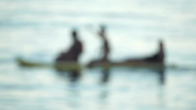 Defocused sea ocean beach of hotel or resort with Lounge bed on hot summer day. Abstract bokeh background of blurred resting and swimming people on beach at blue sea. Holiday, vacation and recreation.