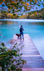 Man with dog on the lake jetty playing with a stick