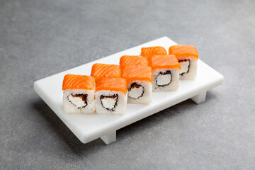 Japanese Sushi roll with salmon on a white stand, gray background