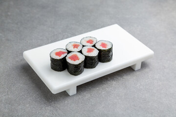 Japanese Sushi roll maki with tuna on a white stand, gray background