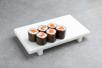 Japanese Sushi roll maki with salmon on a white stand, gray background