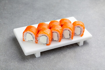 Japanese Sushi roll Philadelphia maxi with cheese on a white stand, gray background
