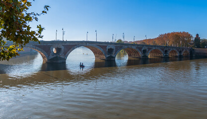 Two fishermen in a boat in the arch of the Pont Neuf over the Garonne, in Toulouse, Occitanie, France